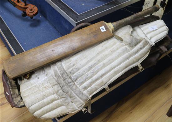A leather cricket bag, pads and a bat